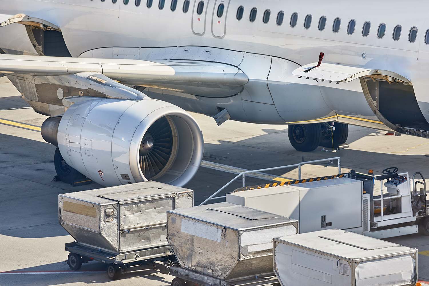 航空機のそばに配置されたコンテナとドーリー